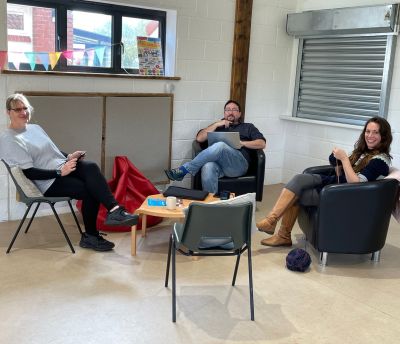 3 residents in the public living room smiling and drinking tea